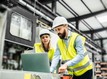 Male and female engineer looking at laptop