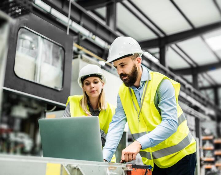 Male and female engineer looking at laptop